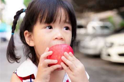 可爱的女孩用手握着苹果，咬着它，咬着它. 亚洲小孩吃新鲜红果. 软焦点. 小 库存照片 - 图片 包括有 乐趣, 聚会所: 205402792