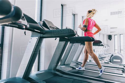 Side view of woman running on treadmill at gym - Stock Photo - Dissolve