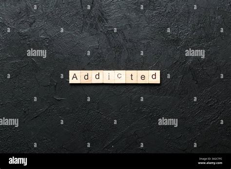 Addicted word written on wood block. Addicted text on cement table for ...