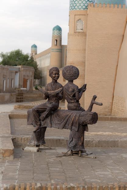 Sculpture of two boys eating melon on wooden bench in front of ancient ...