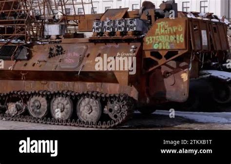 A man walks past a burnt armoured personnel carrier near buildings destroyed in the course of Ukrain