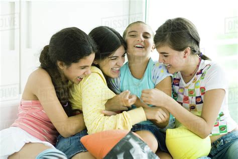 Four young female friends tickling each other and giggling - Stock ...