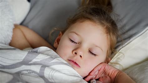Cute little girl sleeping and grinding teeth in dreams, clenched teeth with tiredness and stress ...
