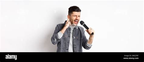 Handsome singer trying to reach high note, singing in microphone and ...
