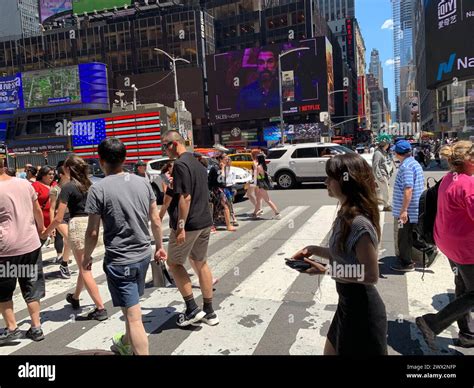Pedestrians are surrounded by video billboards as they cross the street ...