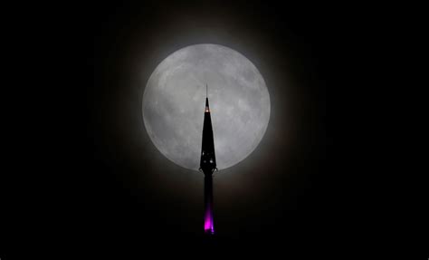 A giant of a moon appears before a giant of a planet undergoing seasonal changes in this natural col