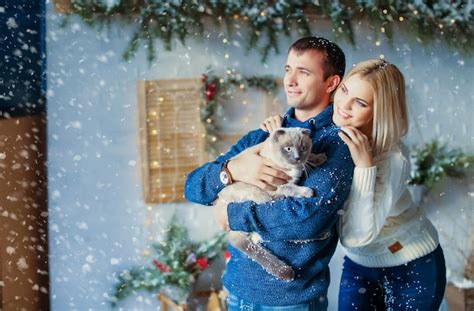 Close up of a couple on christmas eve with a pet cat in his arms ...