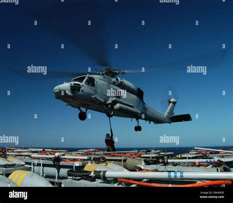 US Navy Aviation Ordnancemen hook a cargo pendant to an SH-60B Seahawk ...