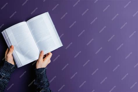 Premium Photo | A pair of hands hold a book open against a purple ...