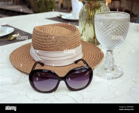 A sunglasses and woven straw sun hat decorated with beige color ribbon ...