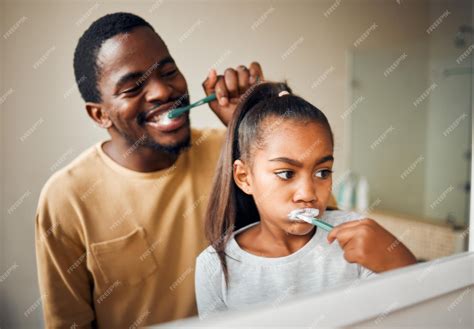Higiene bucal cepillarse los dientes y padre con hija en un baño para ...