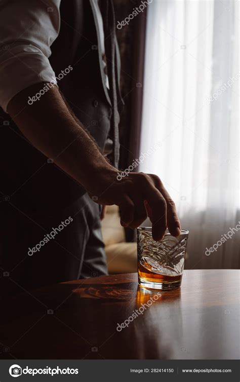 Vertical image of man's hand holding glass of whiskey. Tasting and ...