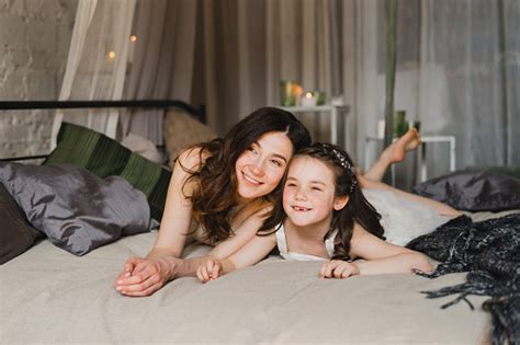 Mother and daughter cuddling on a bed in a kids room