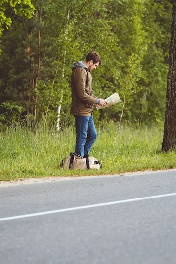 Man with map and bag in hand walking on a roadside | Premium Photo