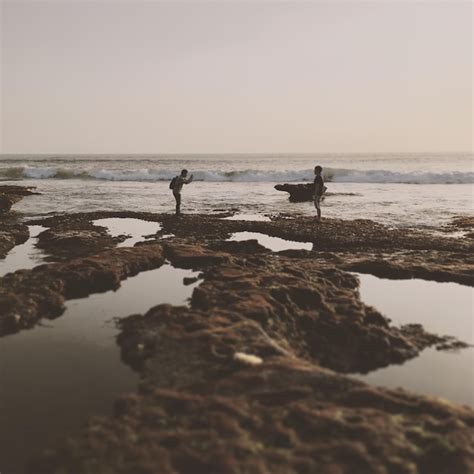 Full length side view of men standing on rock formation at beach ...