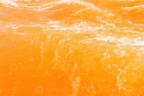 Defocus blurred transparent orange colored clear calm water surface texture with splash, bubble ...