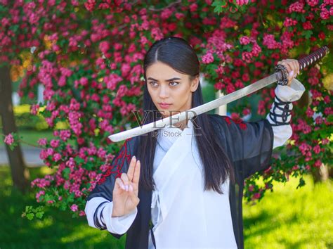 优雅的女孩穿着传统的和服在一个盛开的花园与日本武士刀katana亚洲女战士形象照片摄影图片_ID:419791741-Veer图库