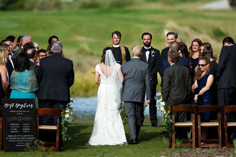 The groom looks at his bride walking down the aisle during their Vail ...