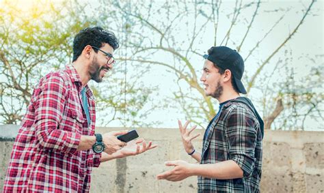 Premium Photo | Two friends chatting while smiling and using cellphone ...