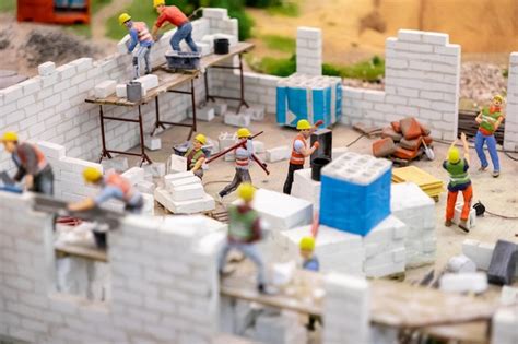 Construction workers building brick walls at a busy site with ...