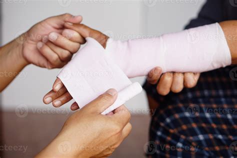 Closeup man's hands are wrapping patient's sprained wrist with elastic bandage. Concept, First ...