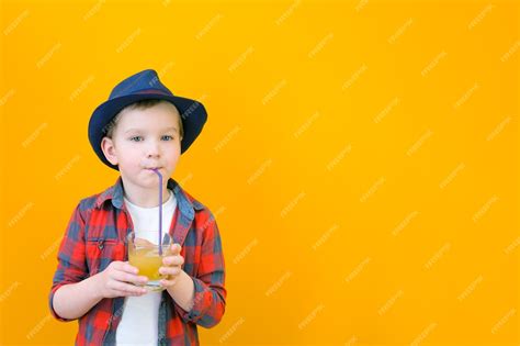 Premium Photo | A boy in a hat drinks juice with a straw. Relaxing ...