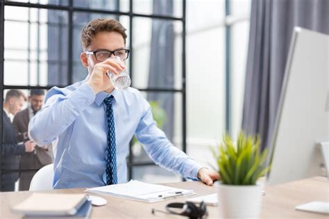 Handsome businessman using pc and drinking water in office area with ...