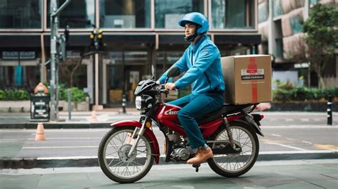 Delivery man wearing blue uniform riding motorcycle and delivery box ...