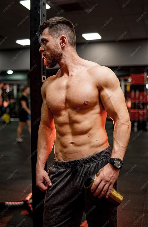 Сильный мускулистый мужчина со спортивным телом молодой бодибилдер без ...