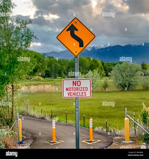 Square Winding Road Ahead and No Motorized Vehicles sign against nature ...