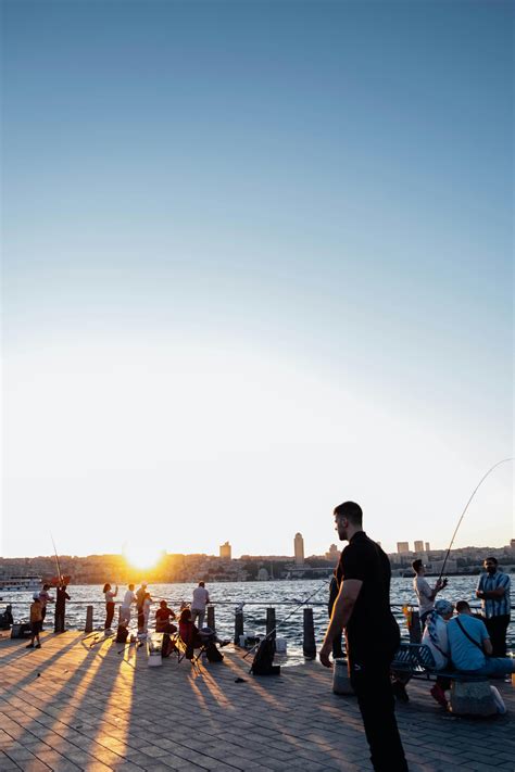 Silhouettes of Fishermen on the Shore at Sunset · Free Stock Photo
