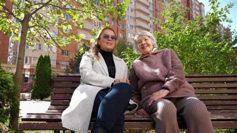 Adult daughter talking to her senior parents on a bench in a park