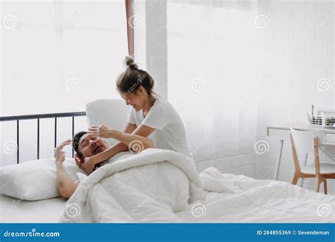 Funny Couple Wife Try To Wake Lazy Husband Up in White Bedroom. Stock ...