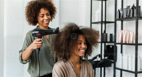African american women engaged in hair styling session in modern salon ...