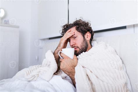 Man being sick having flu lying in bed checking his temperature and ...