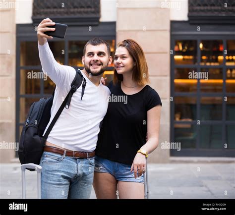 Smiling spanish female and male standing with baggage at street and ...