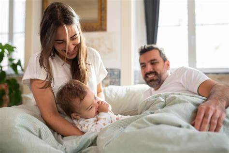 Alegre mulher brincando com seu filho bebê na cama | Foto Grátis