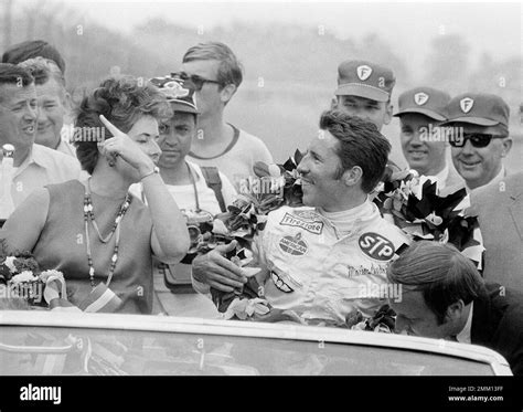 Mario Andretti of Nazareth, Penn., with a garland of flowers around his neck, and accompanied by ...