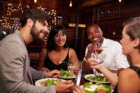 Four friends enjoying dinner and drinks at a restaurant - Stock Photo ...
