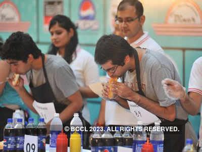 A contestant during the hot dog eating competition, held at India ...