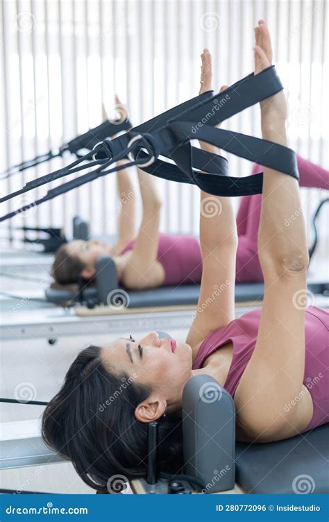 Two Young Asian Women Doing Pilates Exercises on a Reformer. Stock ...