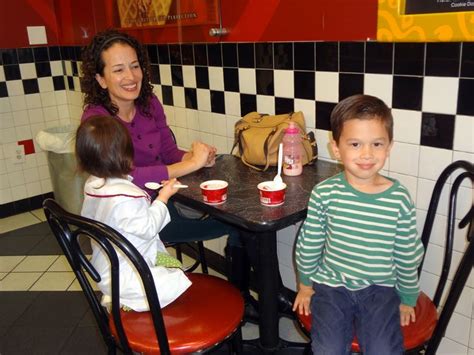 a woman sitting at a table with two children