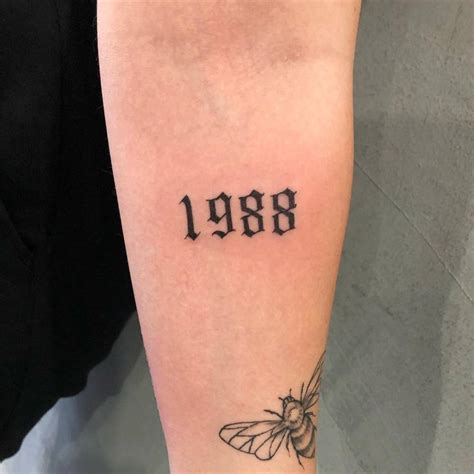 "1988" lettering tattoo on the inner forearm.