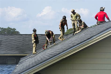 Air Force pararescuemen work to cut through a roof in a simulated ...