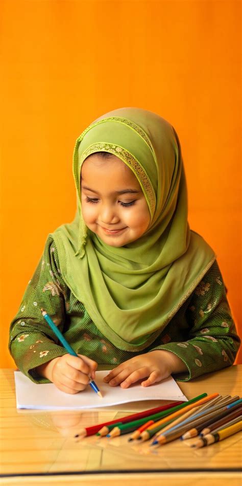 Young muslim girl drawing with colored pencils on bright orange ...