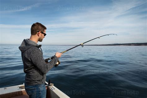 Man Fishing from a Boat in a Stock Photo - PixelTote