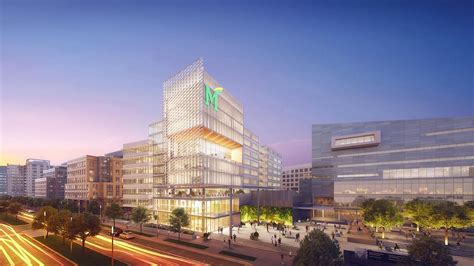 Modern office building with glass facade and illuminated "M" logo, surrounded by trees and pedestrians, representing managed IT services in Pennsylvania.