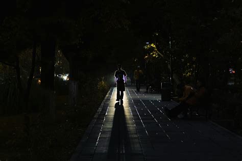 A person walking down a sidewalk at night photo – Free Night Image on ...