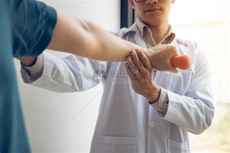 亚洲男理疗师的生治疗师在诊所工作帮助保护有病人在做伸展手术的病人在诊疗室用一个灵活的锻炼带进行伸展高清图片下载-正版图片305789939-摄图网