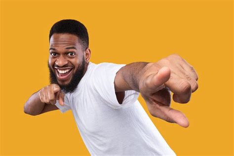 Funny african man posing pointing fingers at camera, yellow background ...
